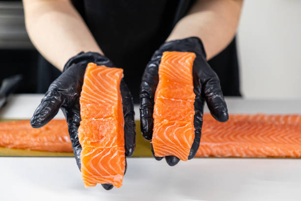 istock two fresh salmon fillet slices held in black gloved hands on a white table for cooking or sushi preparation 2195096662