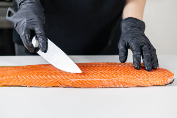 istock cutting raw salmon fillet with a sharp knife and black gloves for precise preparation 2195096795