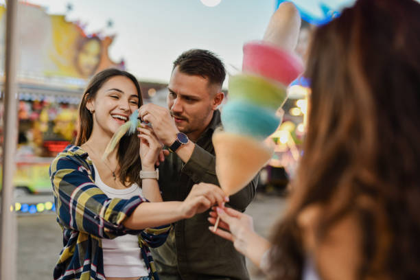 istock Female Smiling When Boyfriend is Feeding Her Cotton Candy at Funfair 2195097903