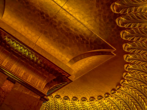A detailed close-up of an ornate golden ceiling featuring intricate geometric and decorative patterns illuminated with warm lighting, creating a luxurious and fascinating visual atmosphere.