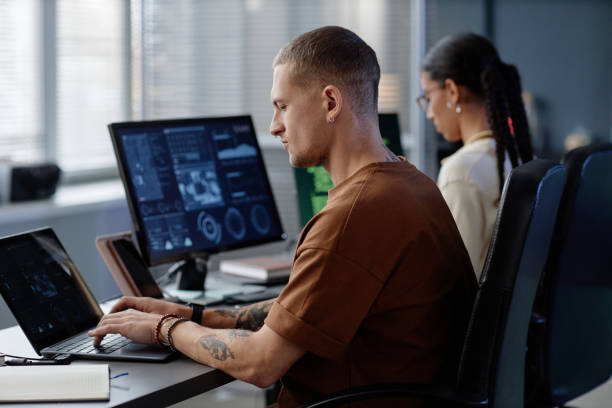 istock Profile of Focused Male Programmer with Septum Coding on Laptop at Working Desk in Office 2195099757