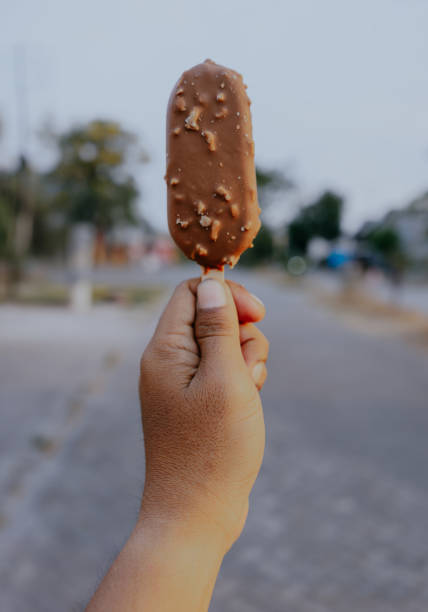 istock Male hand holding ice cream covered with chocolate and almonds. 2195101155