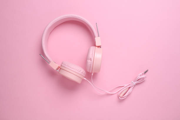 Wired stereo headphones on a pink background. Top view