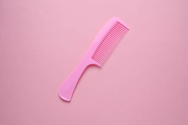Plastic comb on pink background. Hair care