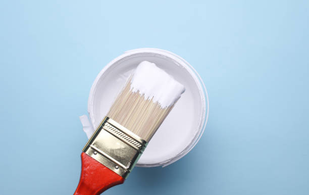istock Paintbrush and can with white paint on blue background. Top view 2195107426