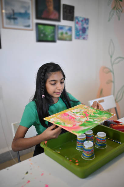 istock Young girl spreading colors and admiring her Creative Fluid Art at a workshop 2195107916