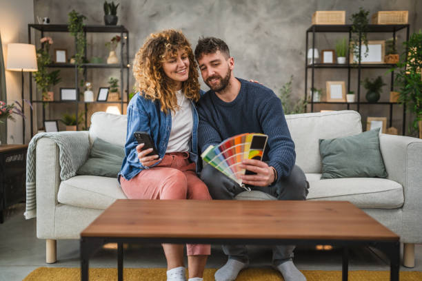 istock Couple hug while selecting vibrant color swatches and use mobile phone 2195109087