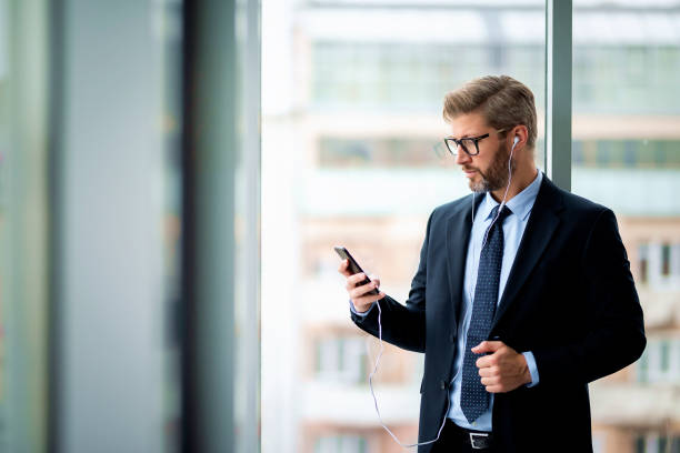 istock Businessman standing at the office and using his smartphone 2195109406