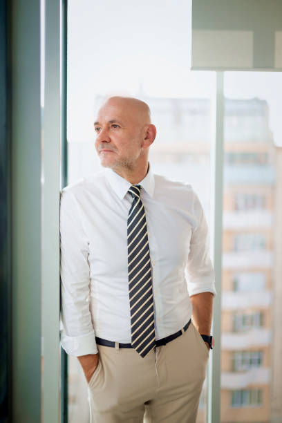 istock Mid aged man standing by the window and looking thoughtful 2195109856