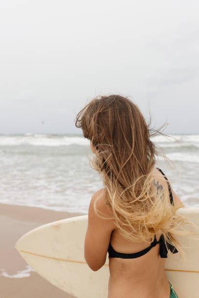 istock Anonymous surfer with surfboard on sea shore 2195110544