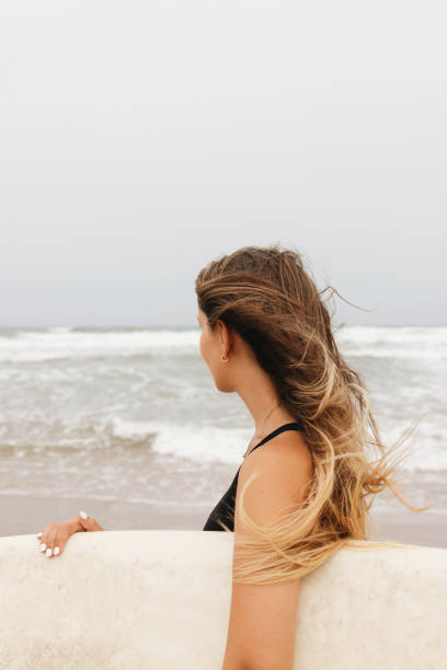 istock Anonymous surfer with surfboard on sea shore 2195110572