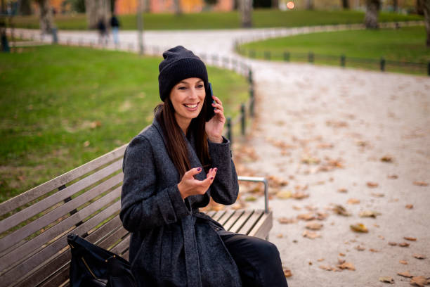 istock Beautiful woman sitting at park and using her smartphone 2195110991