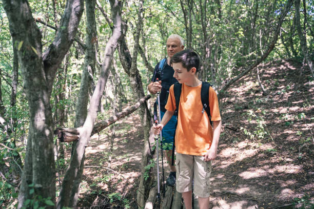 istock Grandparent and child navigate forest's natural path. 2195112093