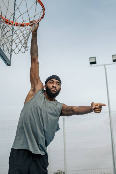 istock Basketball player hanging on basket and pointing with finger 2195113937