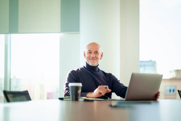 istock Mid aged businessman working on a laptop in a modern office 2195115152