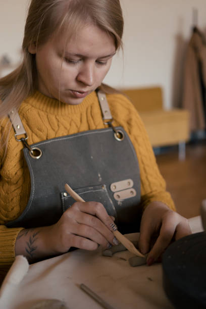 istock Blond woman working in pottery studio making mug handle from clay 2195118557