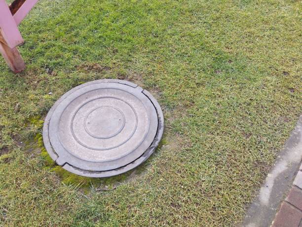 istock Plastic sewer manhole on a green lawn closed with a heavy lid. 2195120090