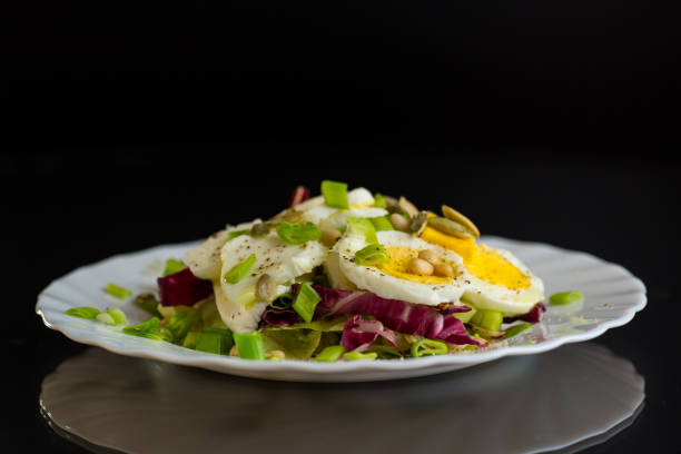 istock Salad with seeds and vegetables in a plate, isolated on a black background 2195121437