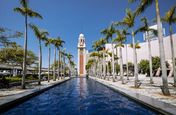 istock Famous Clock Tower in Hong Kong Framed by Palm Trees and Reflective Pool 2195121622