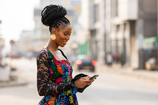istock Stylish African woman using her phone, city backdrop. 2195128524