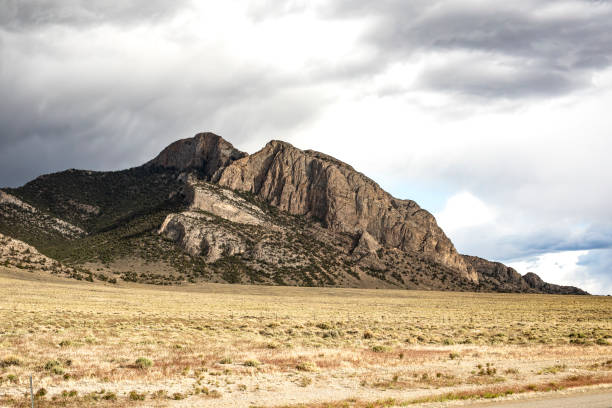 A striking mountain peak set against a broad, grassy plain and dramatic skies. Captures an awe-inspiring natural marvel, perfect for conveying tranquility, exploration, and the beauty of untouched wilderness.