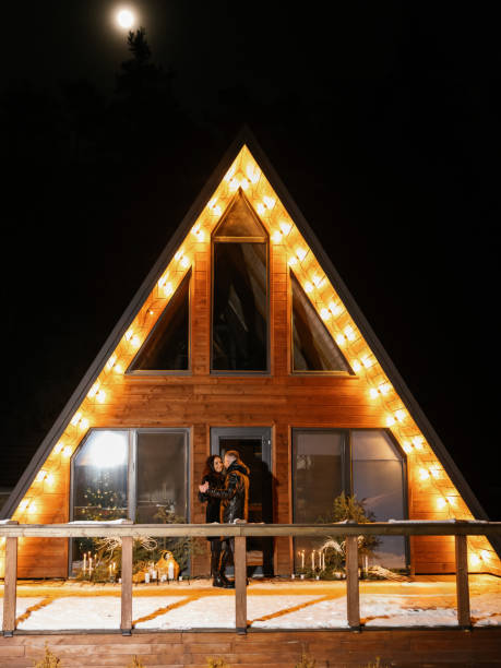 istock Couple hugging in front of illuminated chalet at night 2195132612