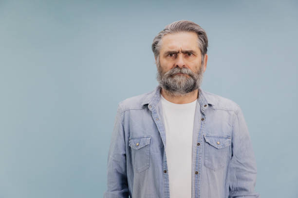 istock Serious senior man with grey beard frowning on blue background 2195133037