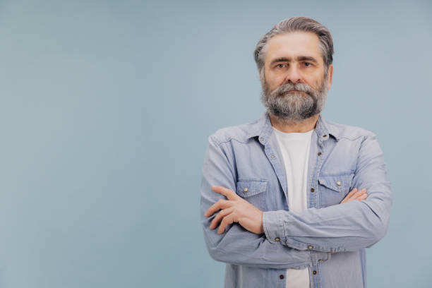 istock Confident senior man with crossed arms posing on blue background 2195133071