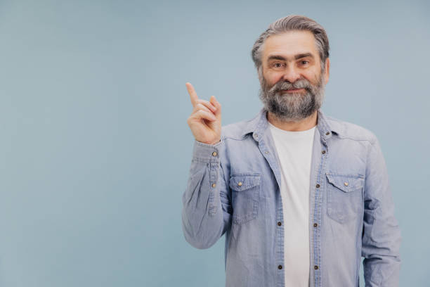 istock Smiling senior man pointing up with index finger on blue background 2195133072