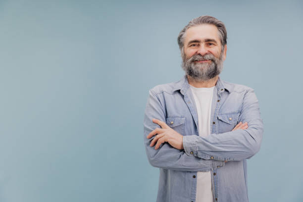 istock Smiling Senior Man with Crossed Arms on Blue Background 2195133180