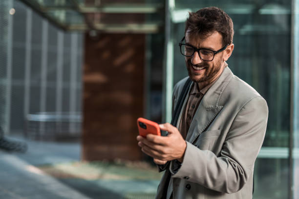 istock Happy elegant businessman using mobile phone in the city 2195134369