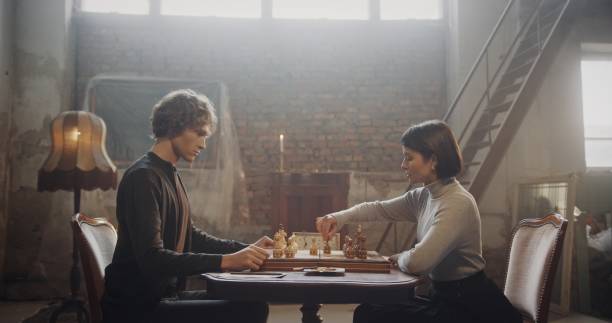 istock Focused chess game between young man and woman in a rustic loft with vintage decor 2195134525