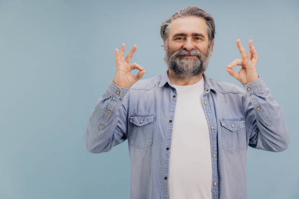 istock Smiling Senior Man Showing Ok Sign with Both Hands on Blue Background 2195134813