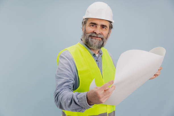 istock Senior engineer wearing safety helmet and vest holding blueprints 2195135074