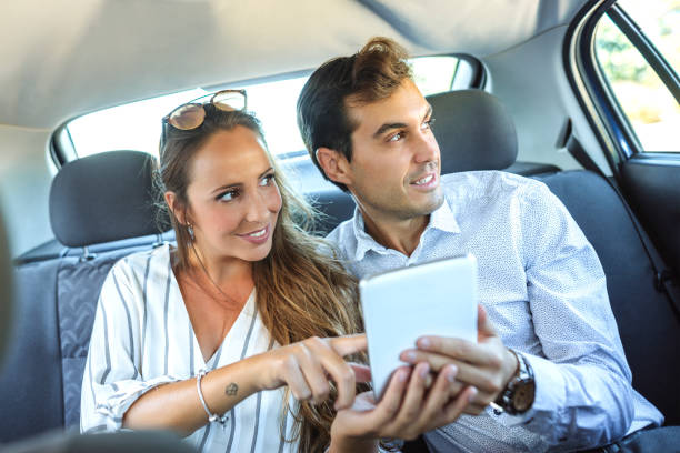 istock Couple in car back seat looking at a tablet 2195135629