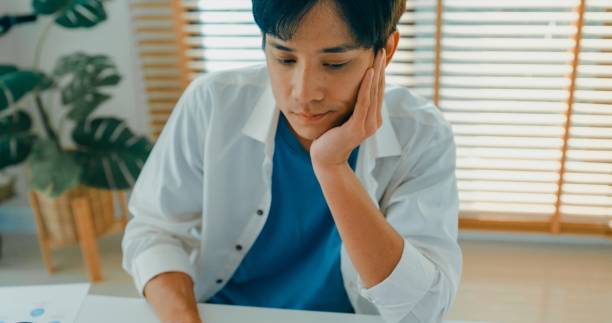 istock Closeup of young Asian man taking a break to stretch while working from home, emphasizing the importance of ergonomics and relaxation. Remote work and finance. 2195136975