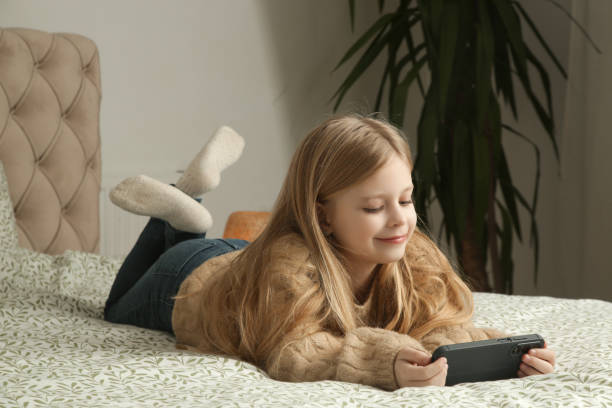 istock Cute little girl using smartphone at home 2195137086