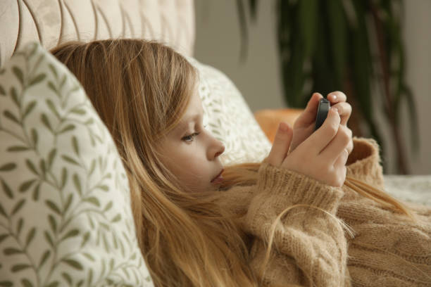 istock Cute little girl using smartphone at home 2195138097