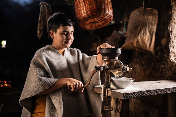 Teenager boy using corn grinder in a farmhouse