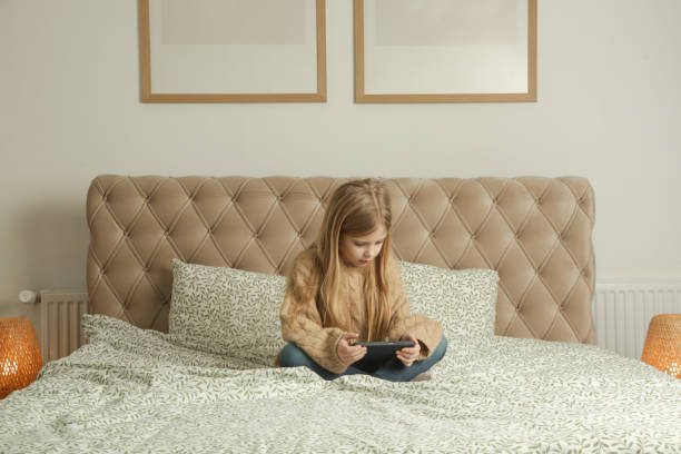 istock Cute little girl using smartphone at home 2195139287