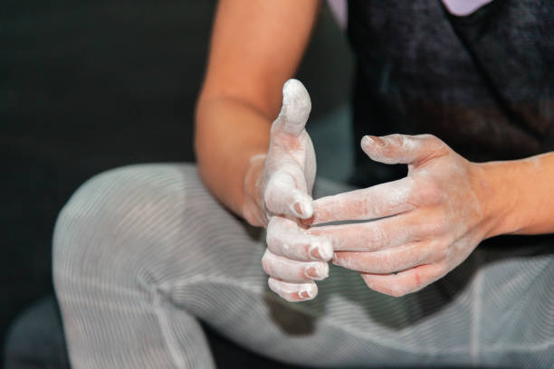 A close-up view of a climber's hands covered in white chalk, preparing for a climb.
