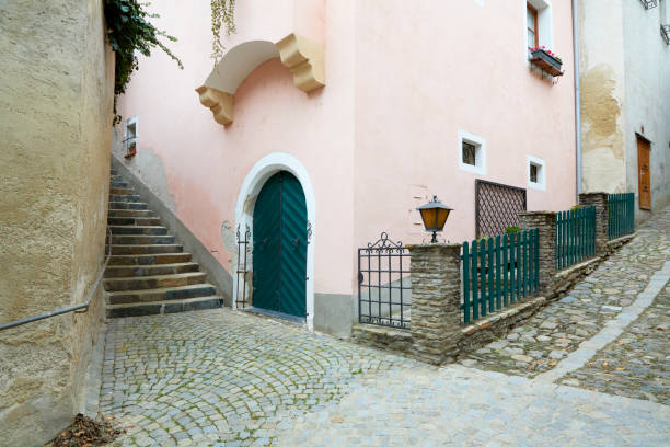Beautiful medieval building with arch doors and cobblestone walkway surrounded by  iron fence and lighting fixtures