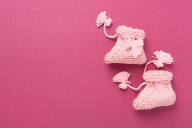 istock Pink baby booties on color background, top view 2195144795