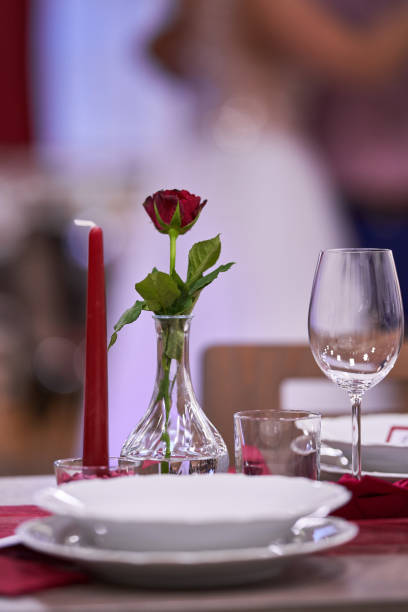 A beautiful table arrangement featuring a red rose and candle, evoking romance and elegance.