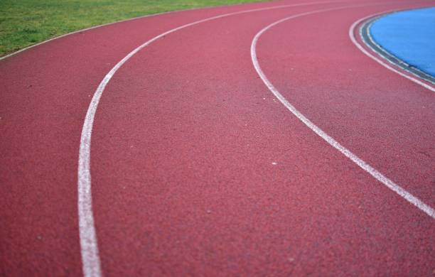 istock Red running track curve with green grass in left side. 2195149851