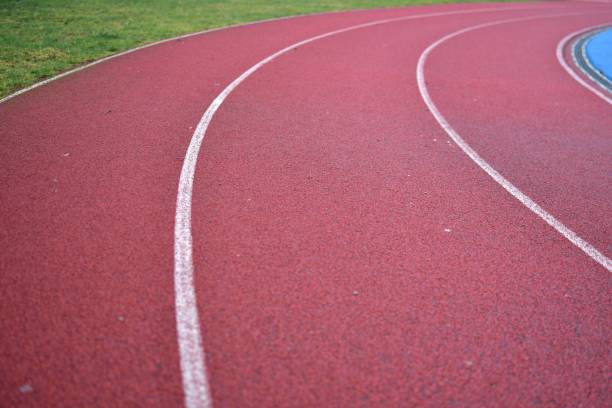 istock Red running track curve with green grass in left side. 2195149888