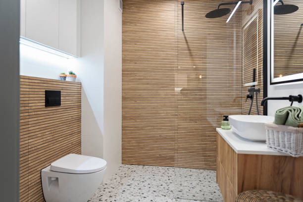 istock Interior decor. Ceramic bathroom sink with black water tap and brown striped tile on the wall and shower with glass. Tiled floor with textured effect and toilet.Real estate. 2195155181