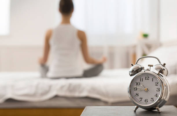 istock Morning yoga. Alarm clock standing on bedside table 2195156188