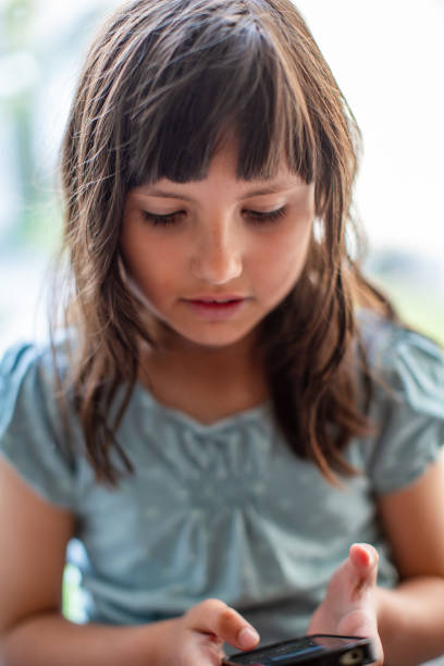 istock Young brown haired girl looking at a phone screen 2195156553