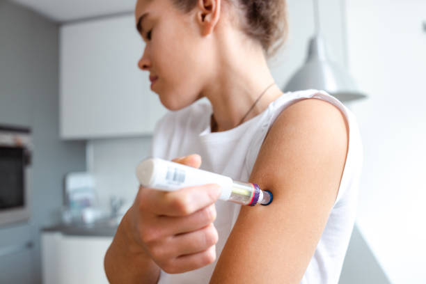 istock Woman self-administering a medical injection 2195157779